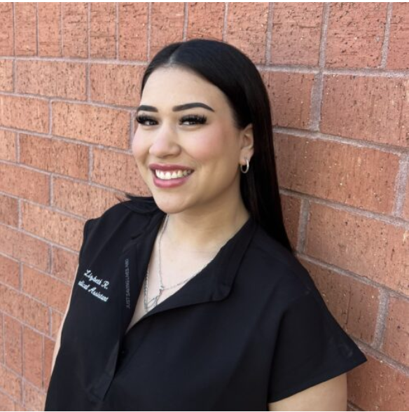 Liz in black scrubs in front of brick wall